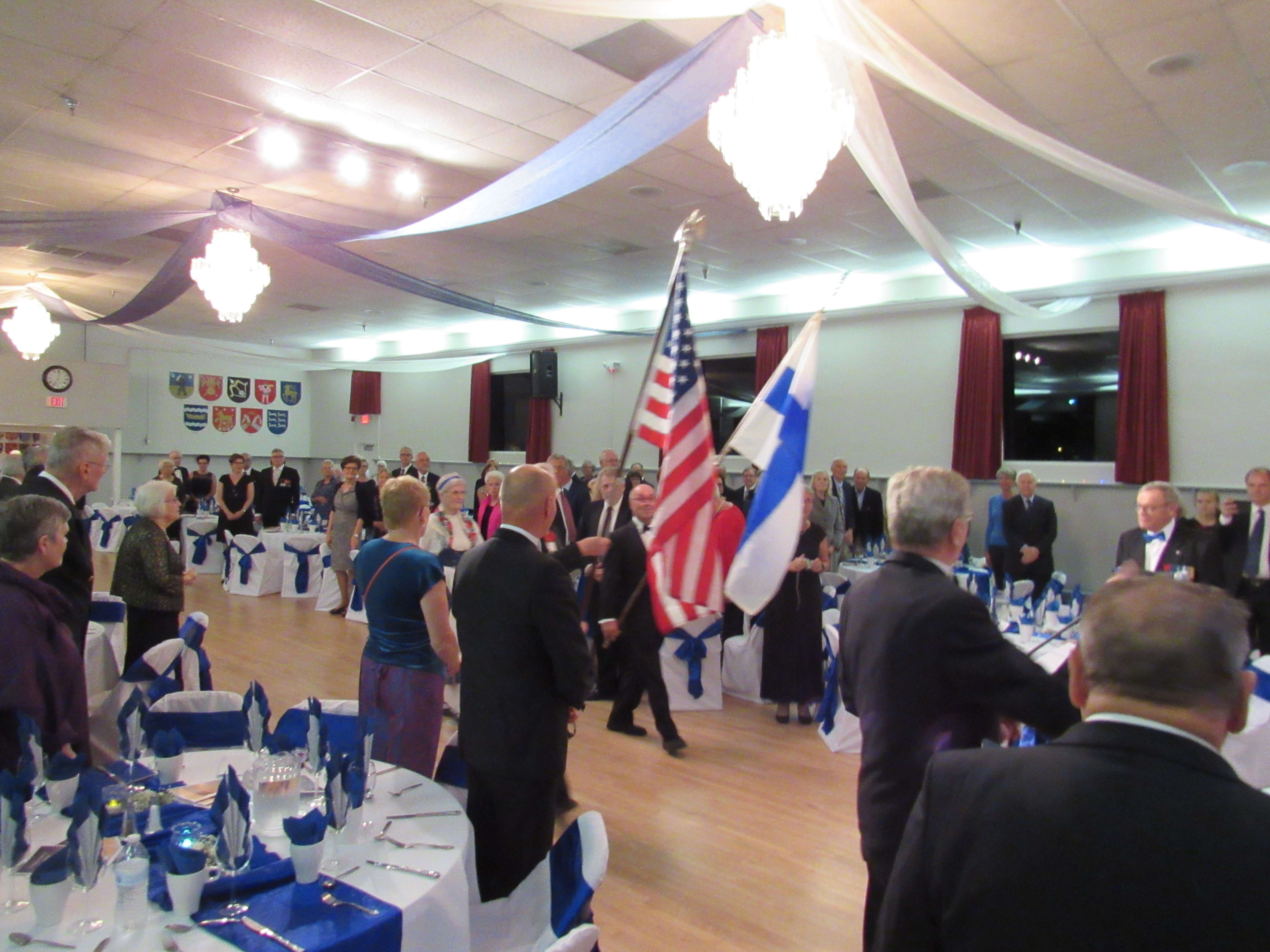 Suomen ja Yhdysvaltain liput saapuvat juhlasaliiin Suomi Talolla.